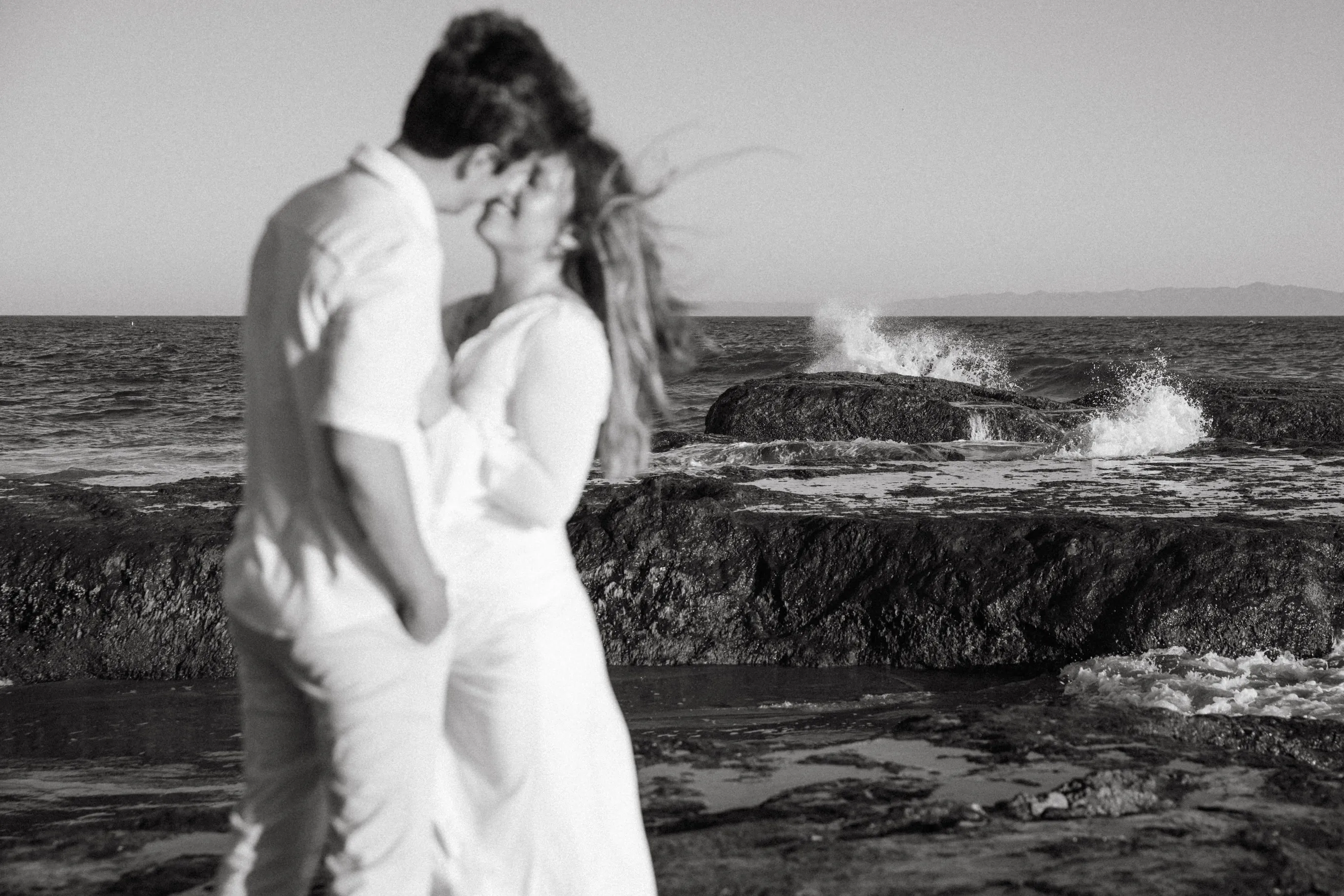 Black and white photo of a couple beside breaking waves