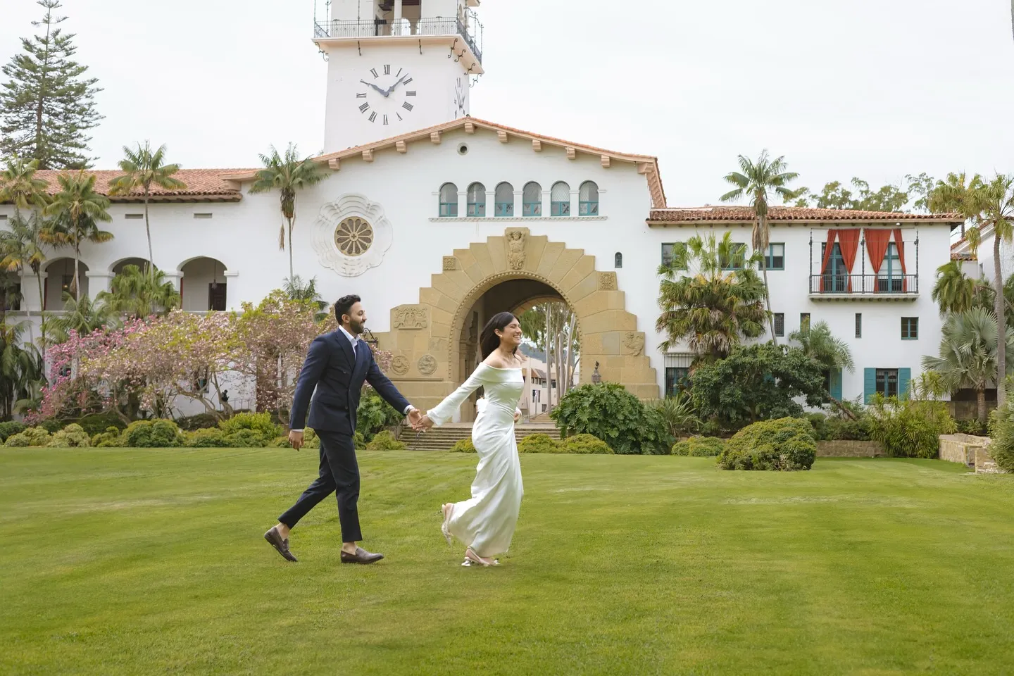 Couple running across the Santa Barbara Courthouse lawn