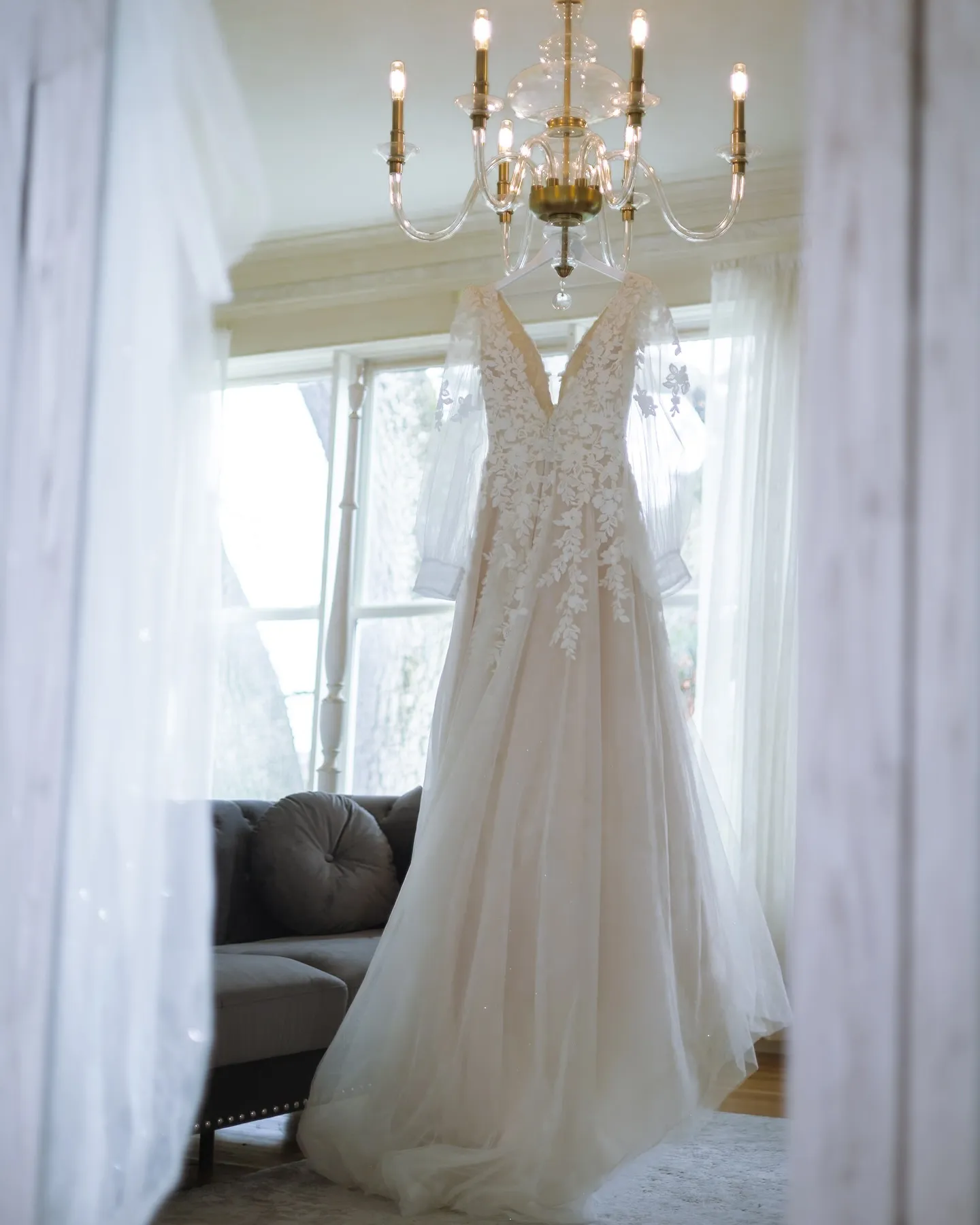 Wedding dress hanging in window light before the ceremony