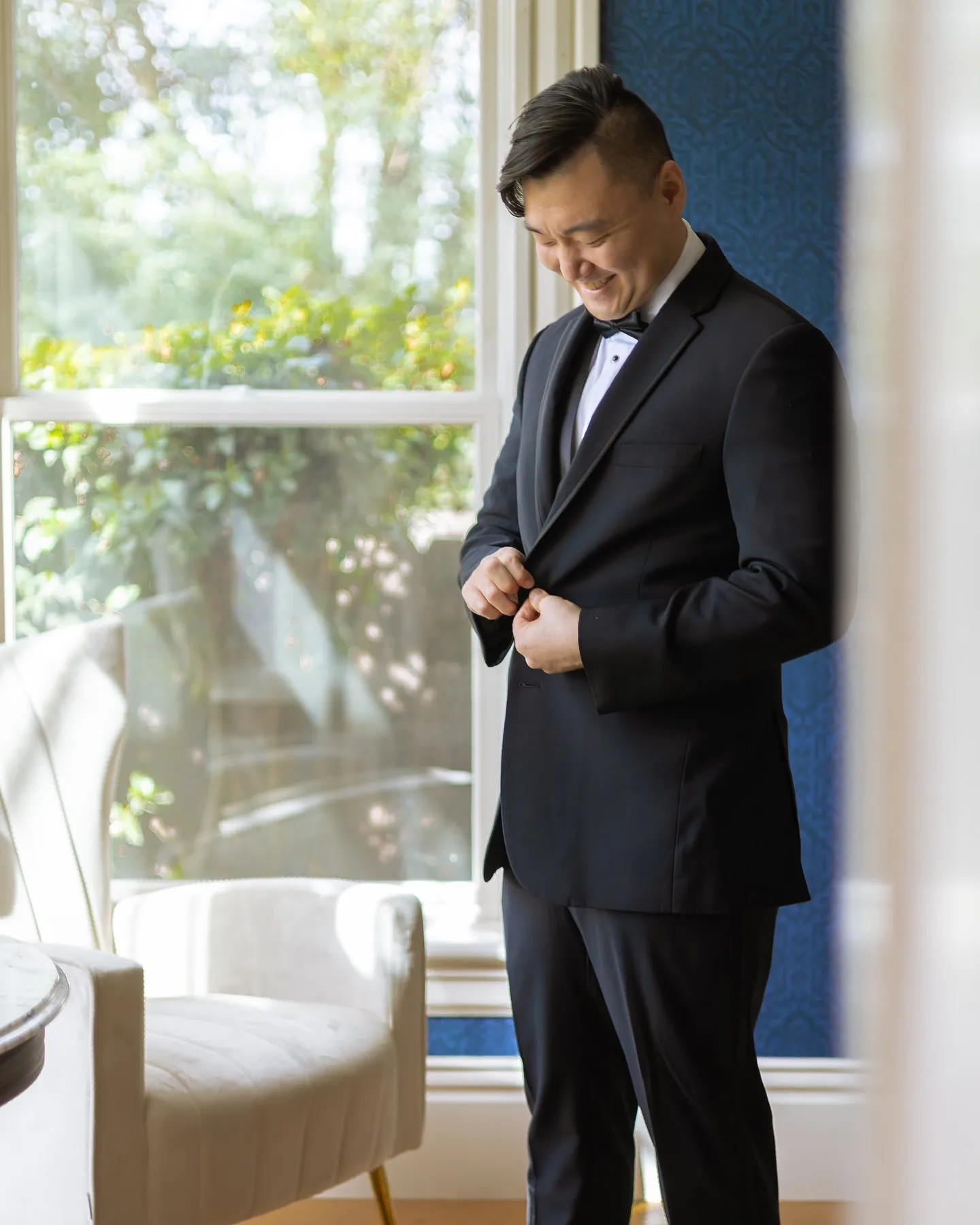 Groom buttoning his tuxedo jacket before the ceremony